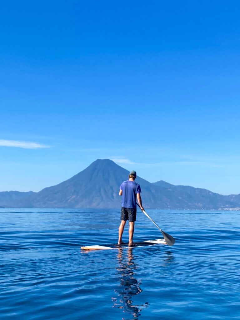 Man in blue shirt on paddle board in Lake Atitlan Guatemala.