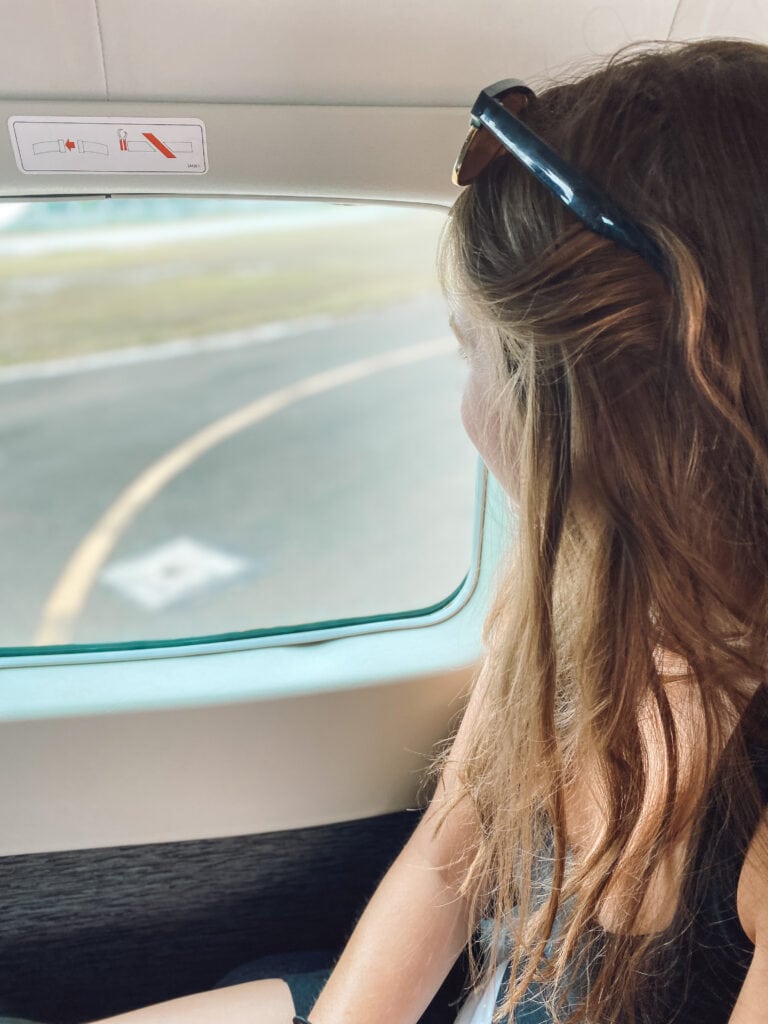 Sarah looks out window at tarmac before flight takes off for Blue Hole in Belize