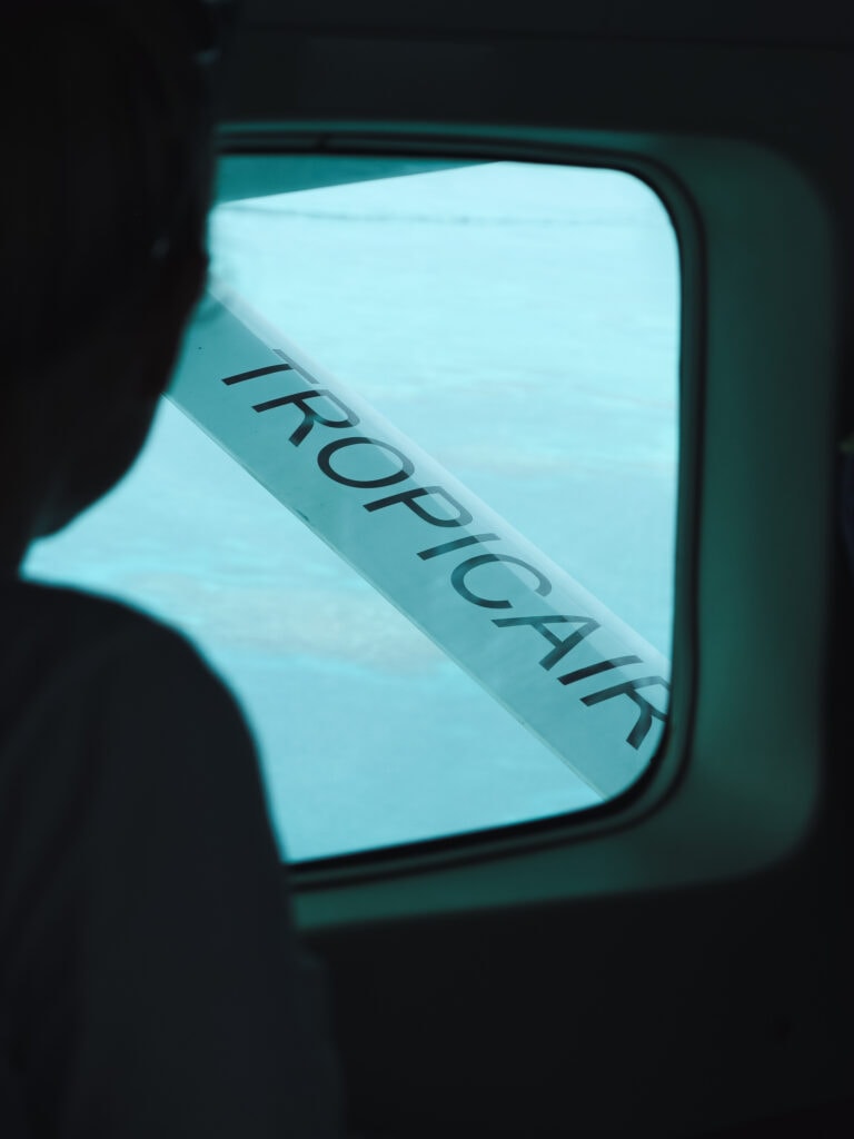 A woman looks out a plane window over the Belize Barrier Reef.
