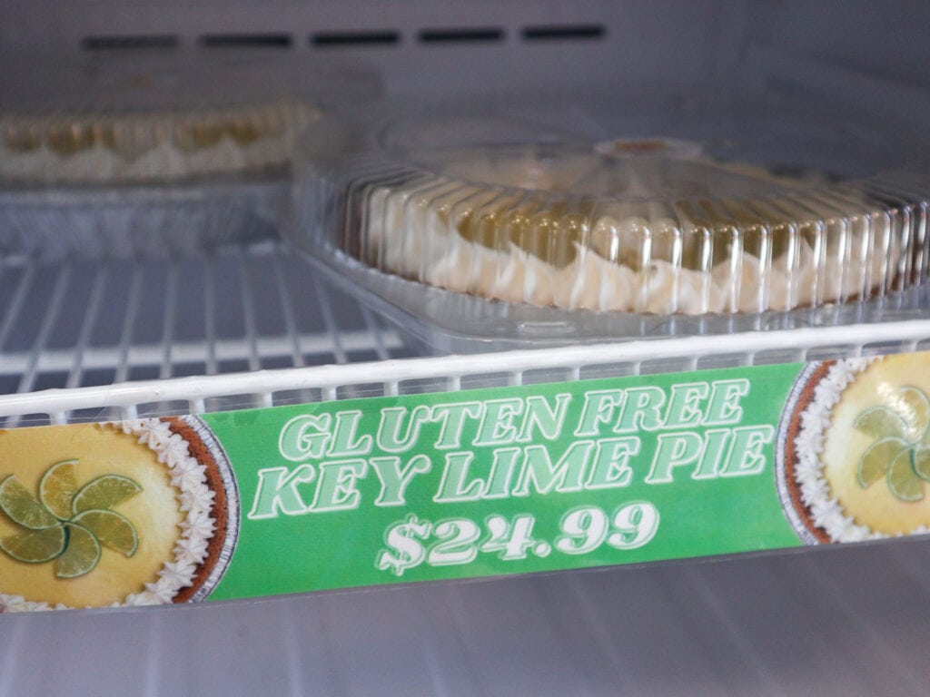 A freezer shelf with a frozen pie and a green sign that reads gluten free key lime pie $24.99.