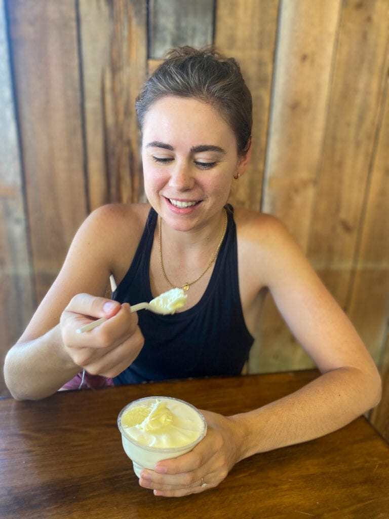 Sarah, a white woman with brown hair and a black tank top, holds a spoonful of key lime pie filling and looks down at it.