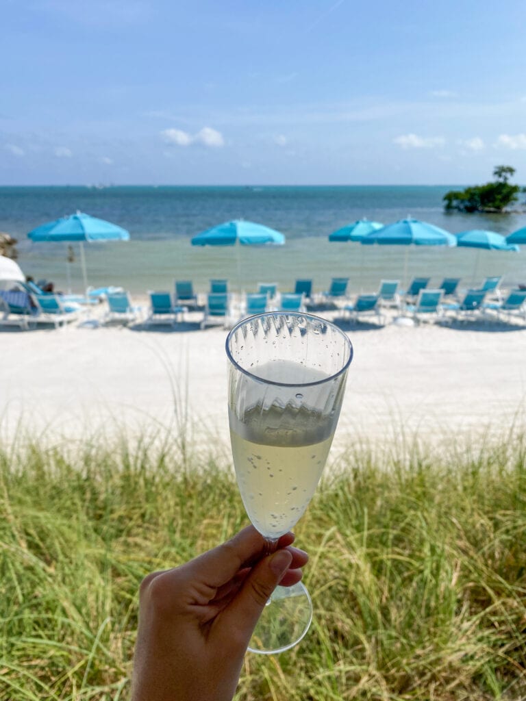 Glass of proescco with blue beach chairs in background.