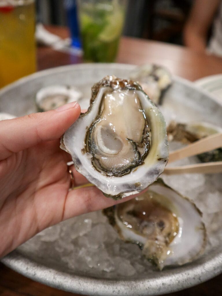 Sarah's hand holding an oyster.