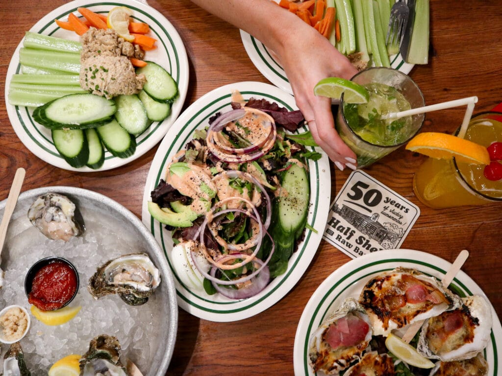 An aerial view of a table with multiple plates of vegetables, salads, and oysters.