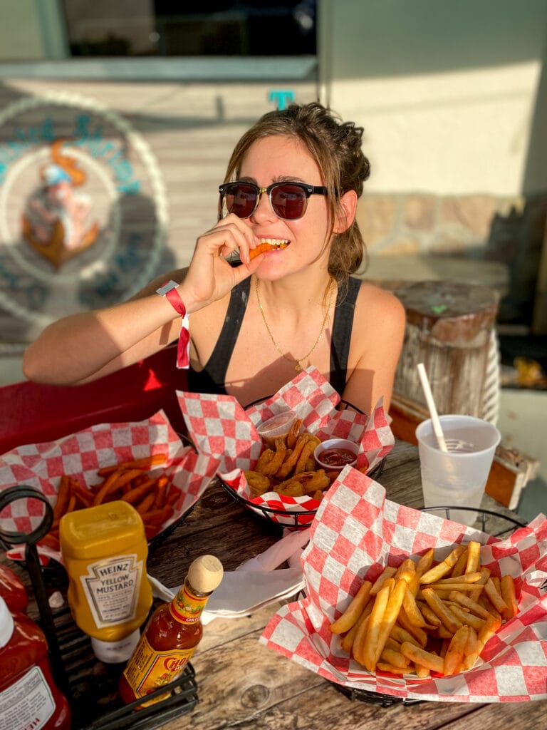 Sarah bites into a sweet potato fry and smiles at the camera.