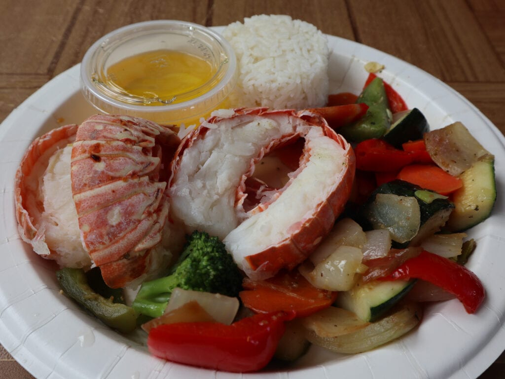 Lobster tail sits on a pile of steamed vegetables.