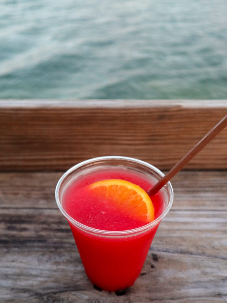 Red rum runner cocktail with ocean in the background.