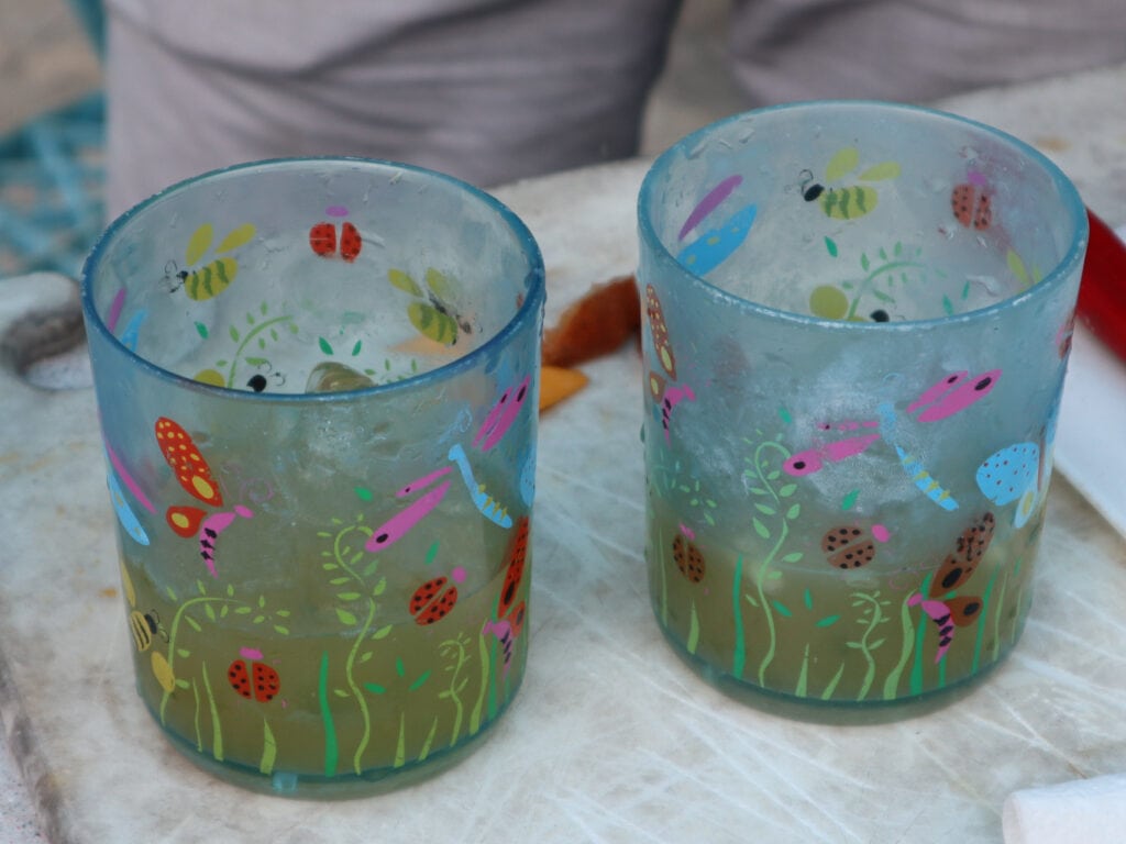 Two blue drinking glasses sit next to each other on a cutting board.