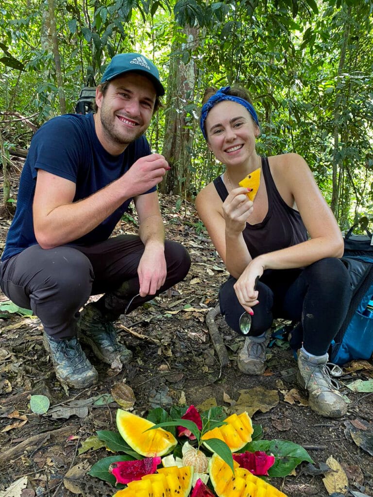 Sarah and Dan smile with fruit in Sumatra jungle
