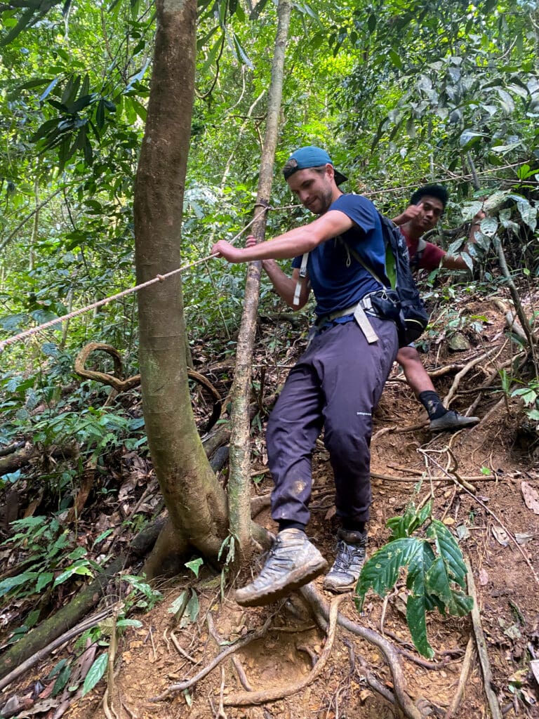 Dan holds onto rope as he hikes steep downhill.