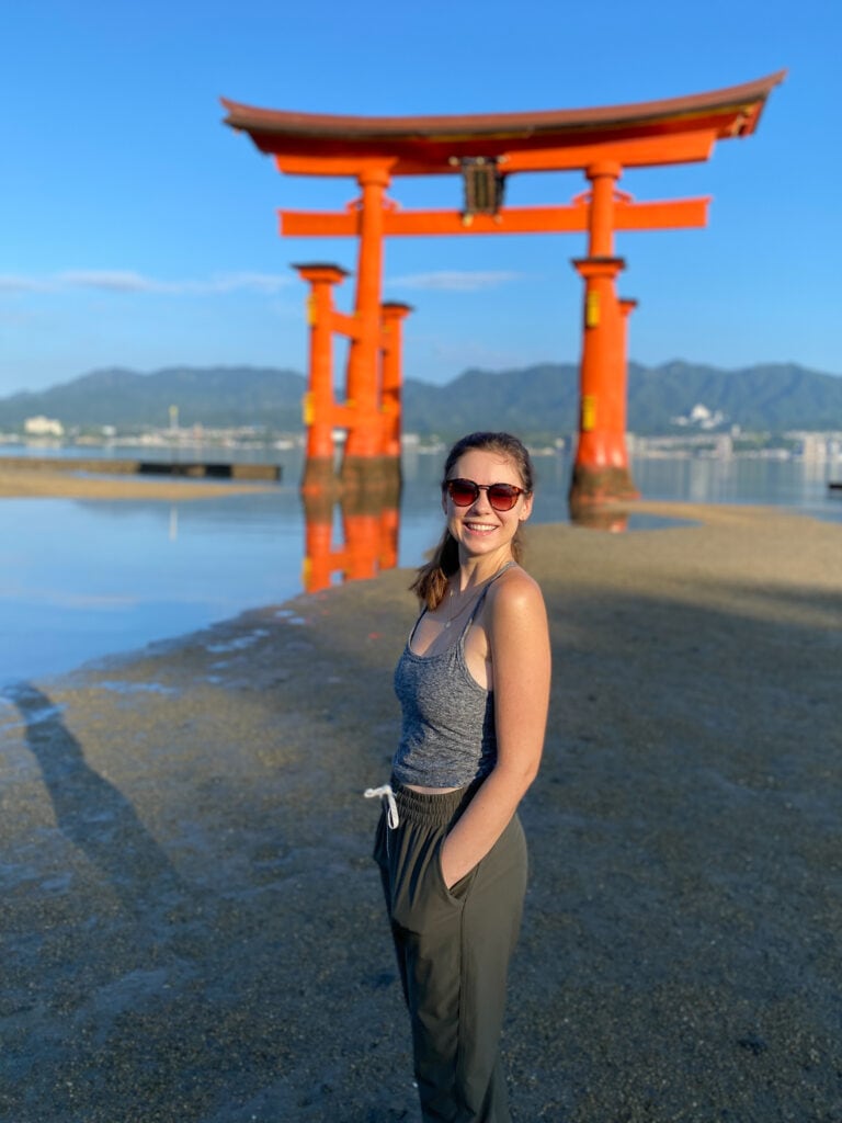 Sarah stands in front of floating torii gate Miyajima Island