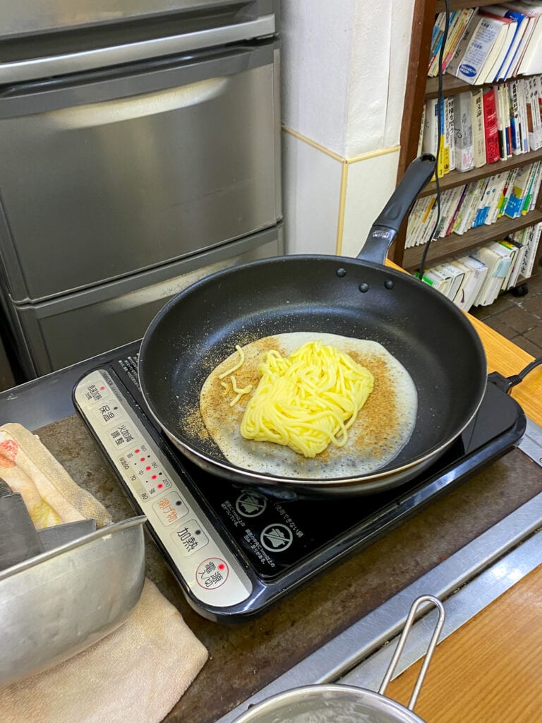 A pan with gluten free noodles, preparing gluten free okonomiyaki.