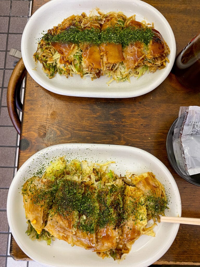 aerial view of table with two plates of okonomiyaki.