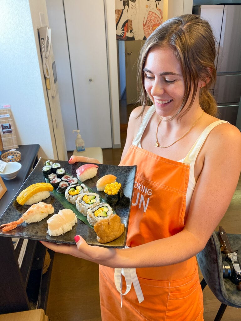 Sarah smiles holding plate of sushi from sushi class in Tokyo