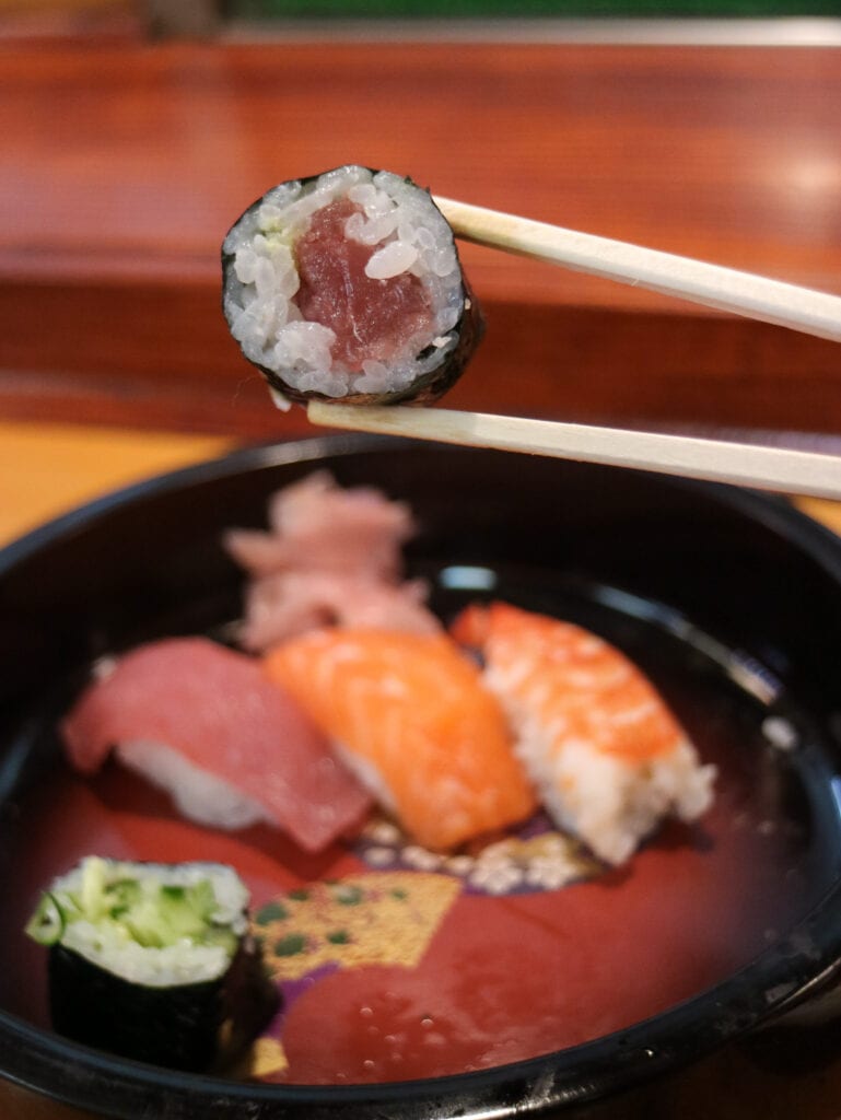 Chopsticks holding gluten free sushi maki roll.