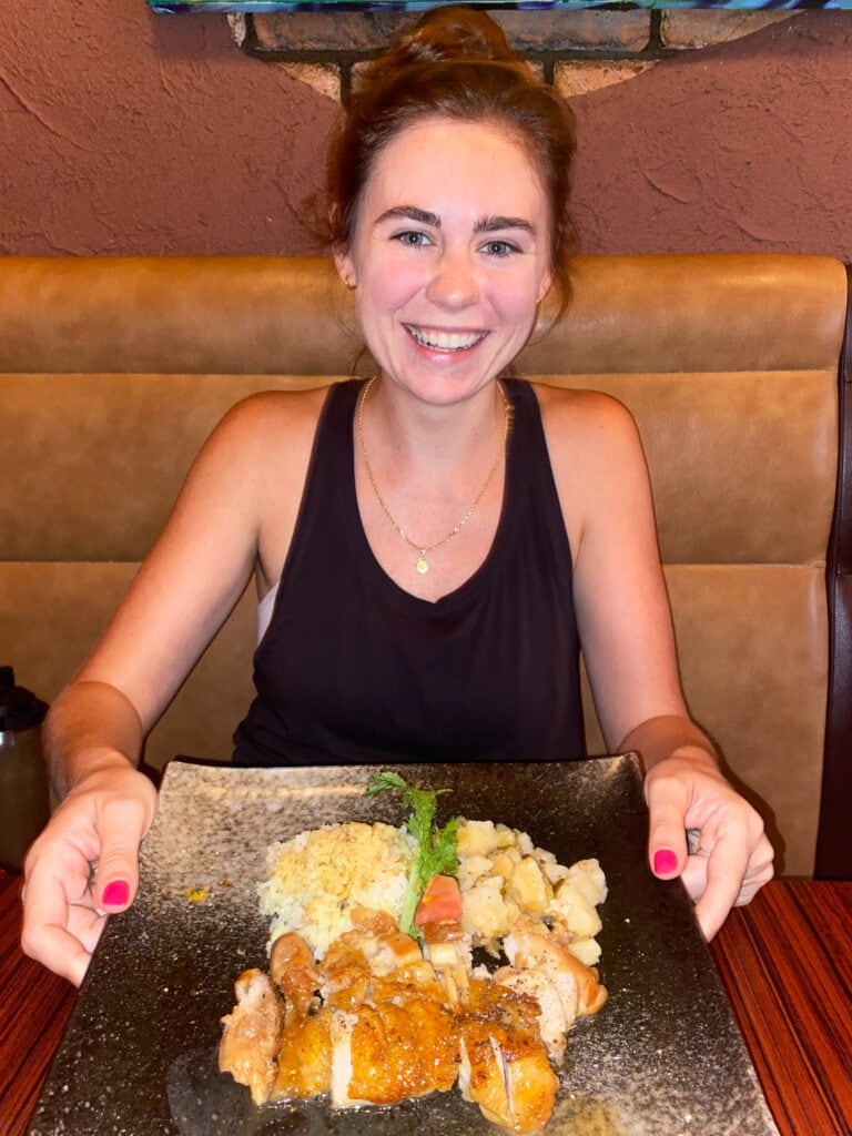 Sarah smiles and hold plate of gluten free teriyaki chicken.
