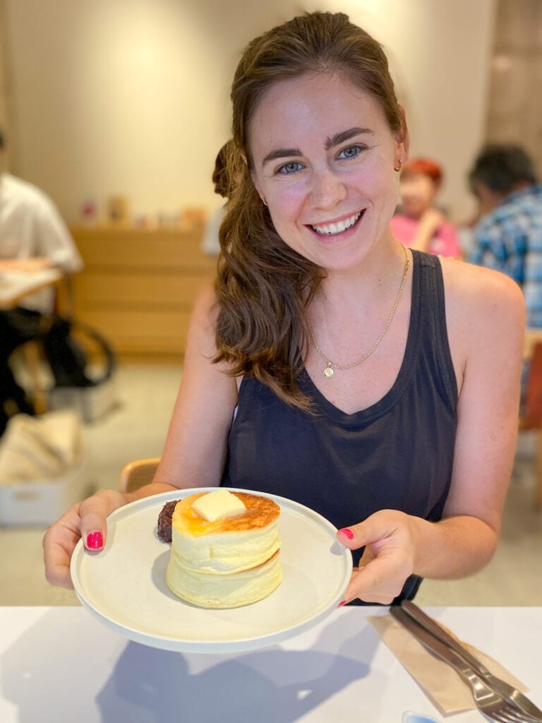 Sarah holds plate of gluten free fluffy pancake and smiles.