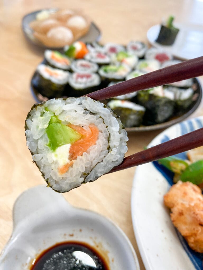 Chopsticks holding sushi roll