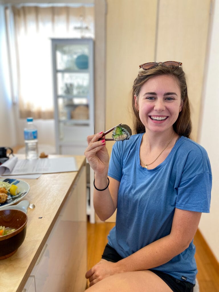 Sarah holding sushi roll and smiling