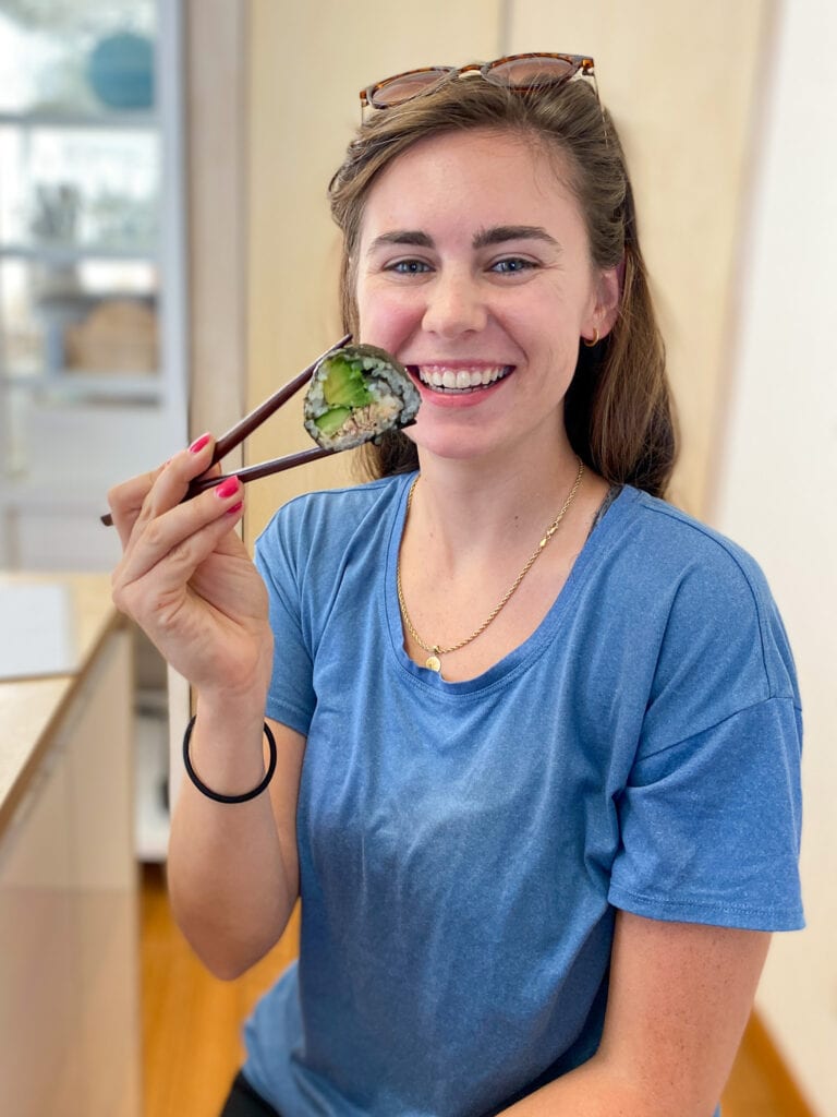 Sarah holding sushi roll with chopsticks