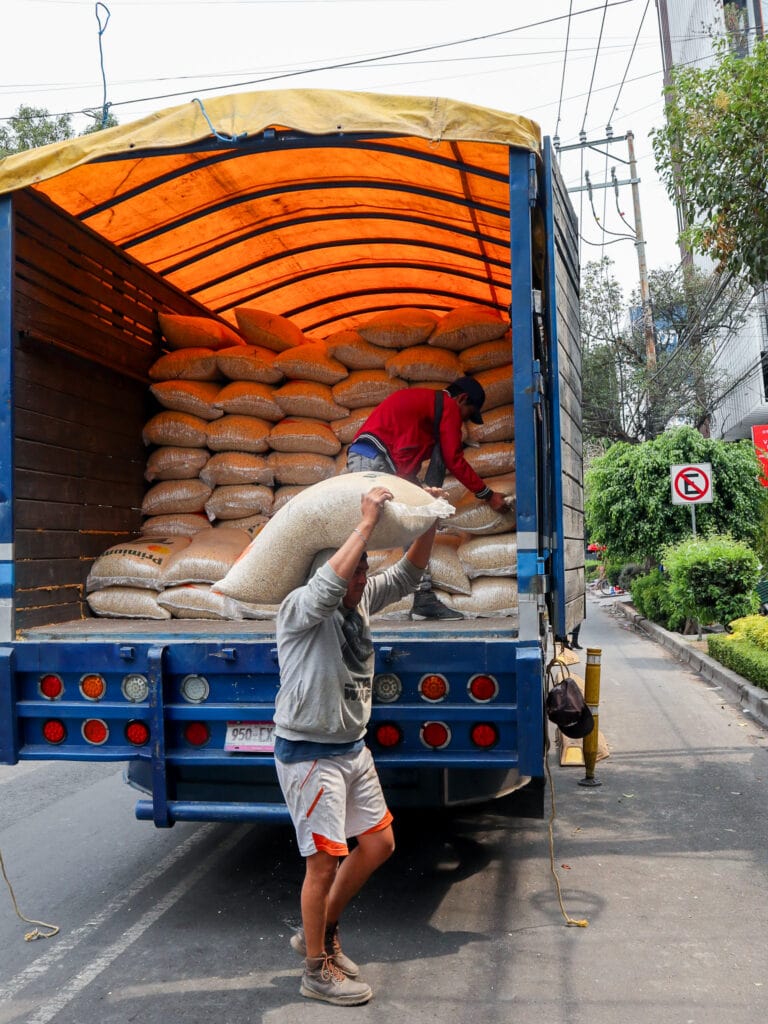 Man carrying bag of corn from truck to tortilleria