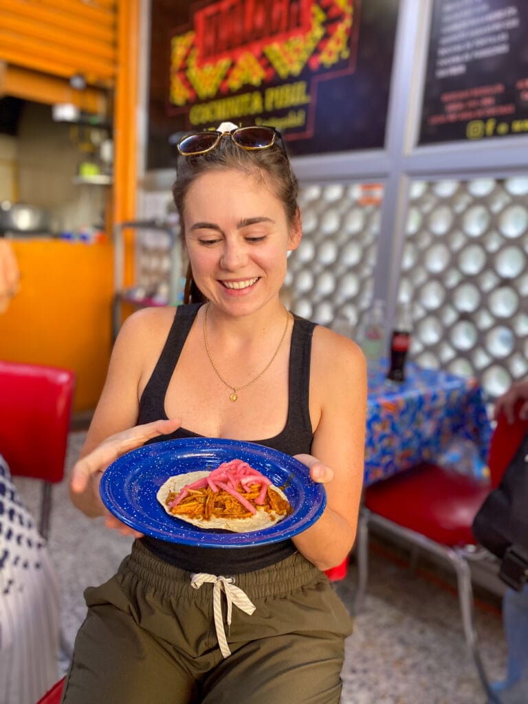 Sarah holding platter of pork taco at Medellin Market in Mexico City.