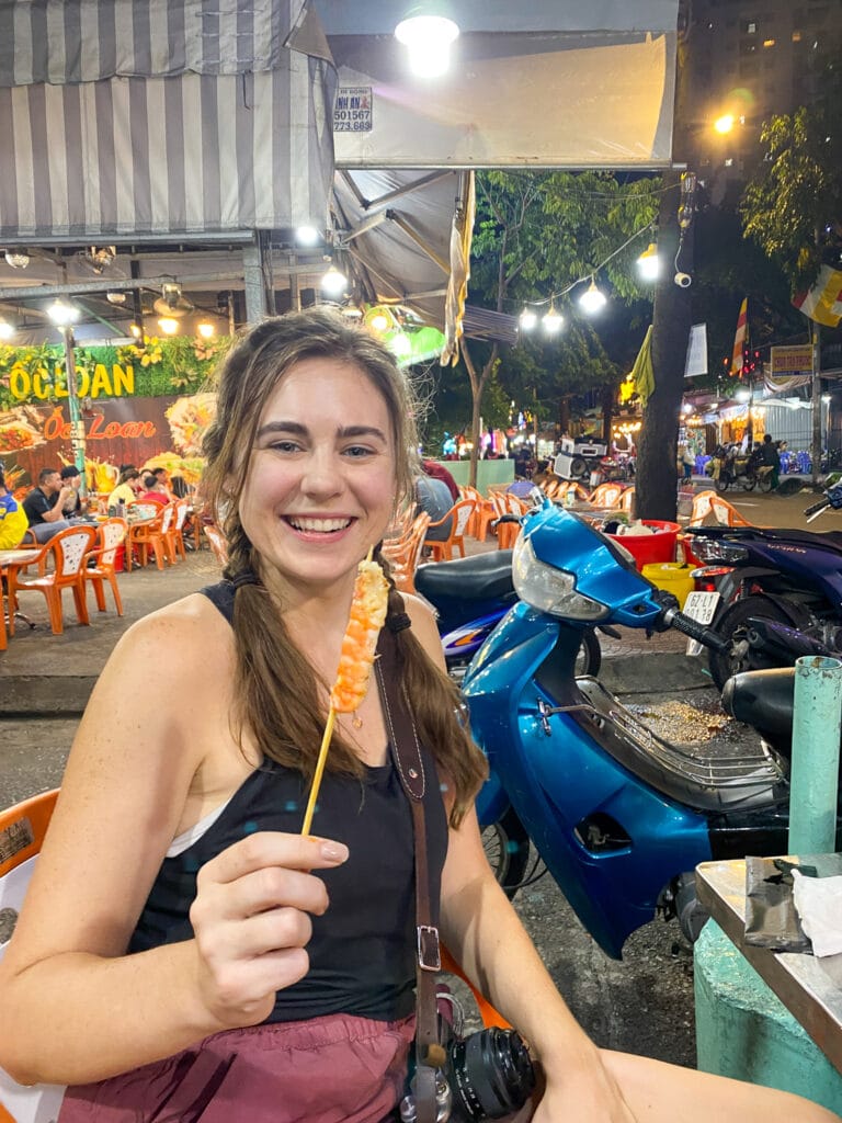 Sarah eating shrimp at street food stall in Ho Chi Minh on gluten free street food tour