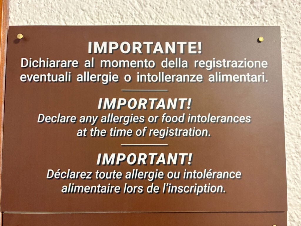 A brown sign that reads "IMPORTANT! Declare any allergies or food intolerances at the time of registration."
