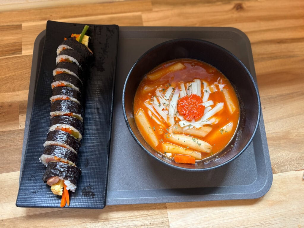 Plate with gluten free gimbap and tteok-bokki on wooden table