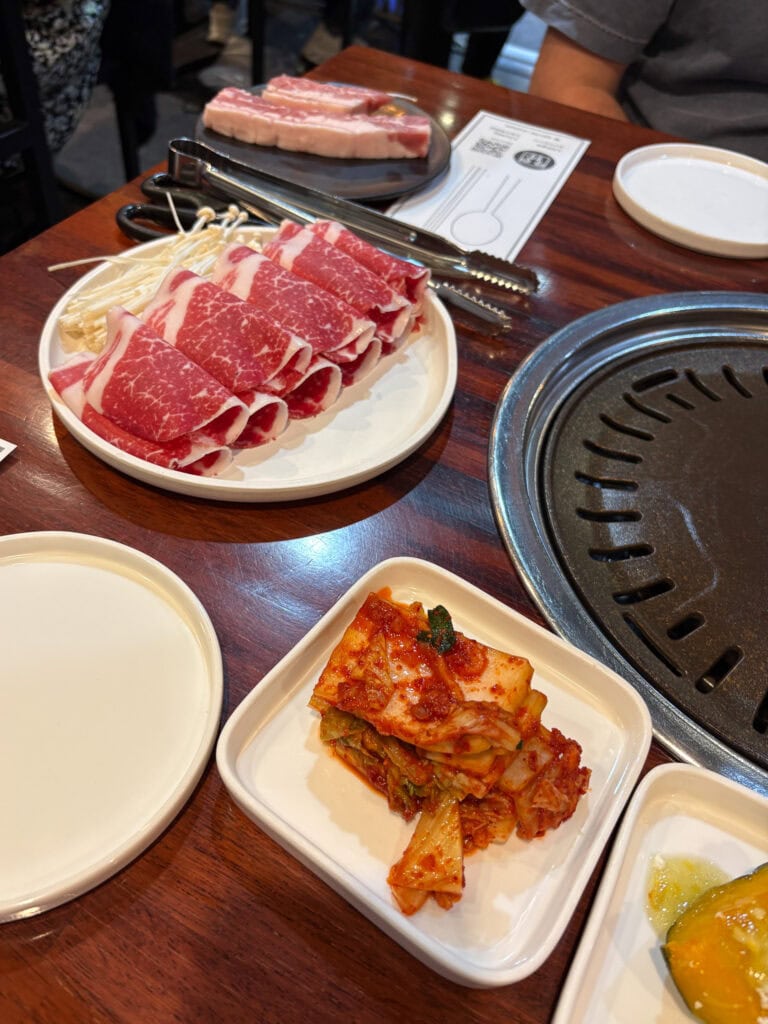 Korean BBQ table with kimchi and meat.