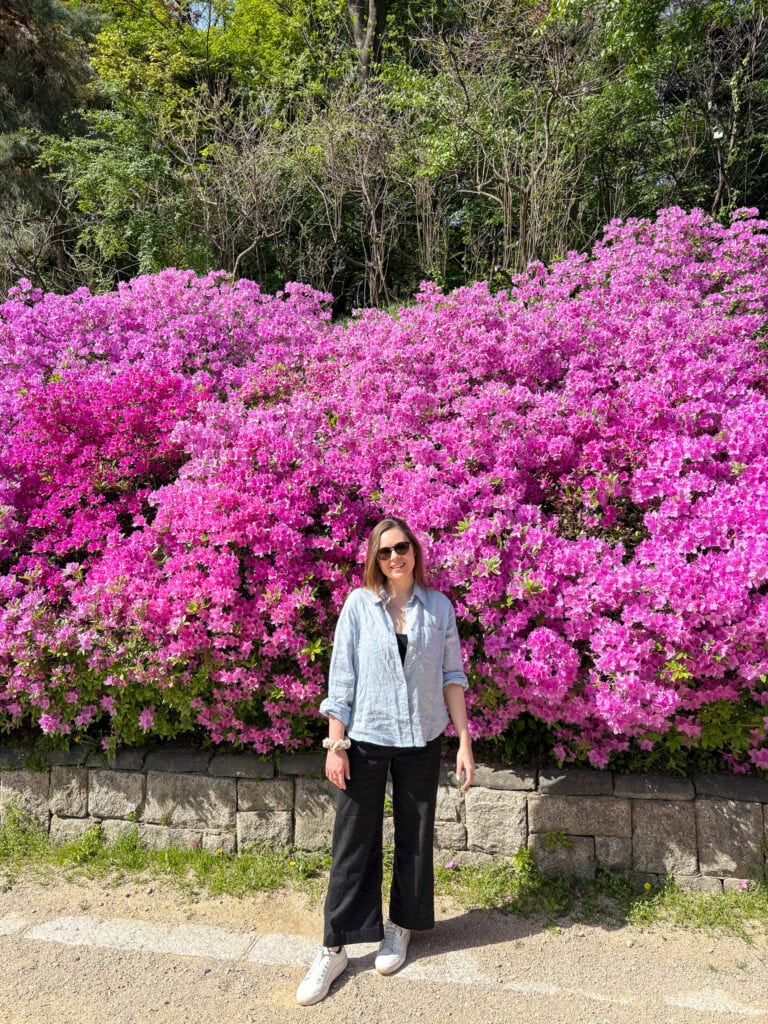 Sarah standing in front of pink azalea flowers.