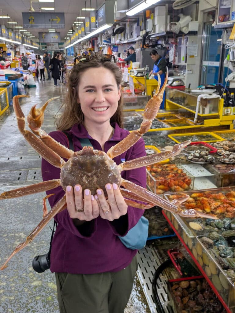 Woman holding a large crab at a seafood market in Busan, South Korea.