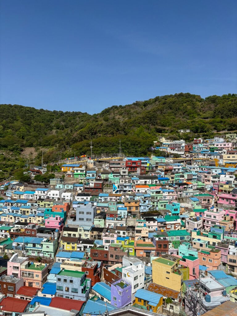 Colorful hillside houses in Busan with clear blue sky above.