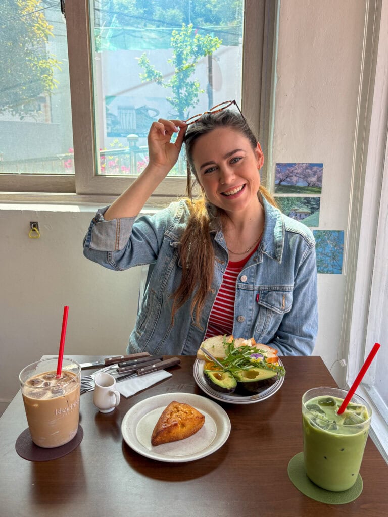 Young woman enjoying a healthy meal at a cafe with smoothies and a pastry.