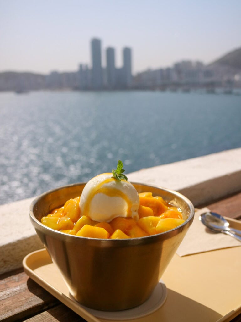 Mango dessert with ice cream on a balcony overlooking the city skyline.