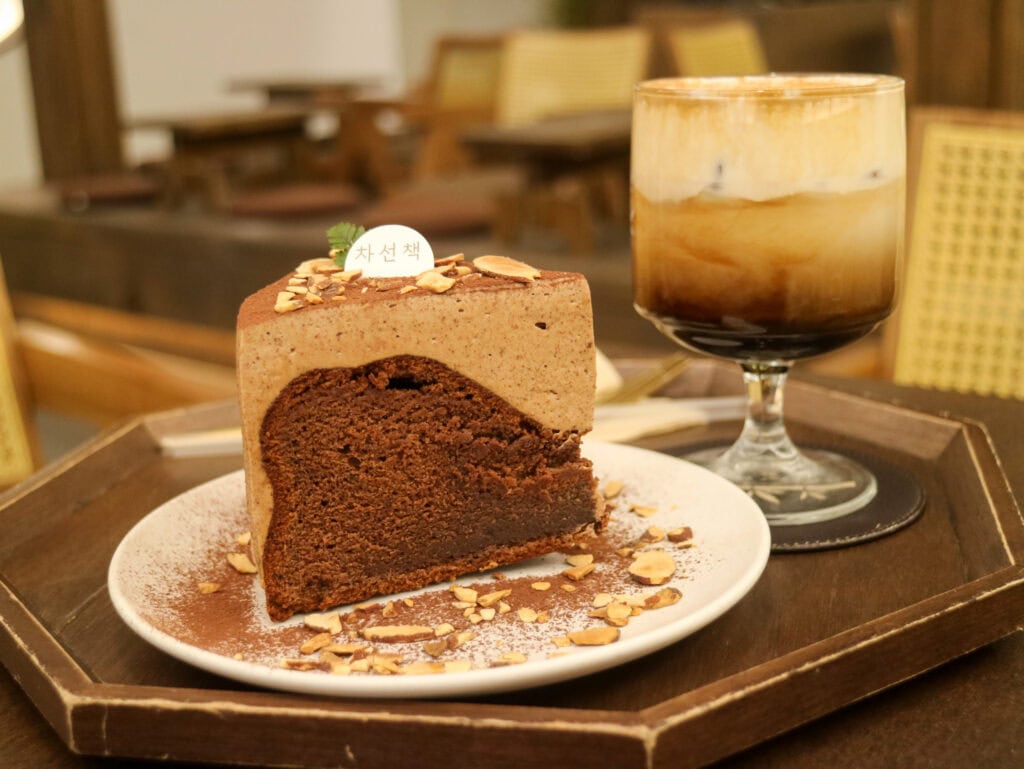 Chocolate cake with coffee drink on a wooden tray in a cozy cafe.