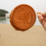 Hand holding a cookie shaped like a 10 South Korean won coin.