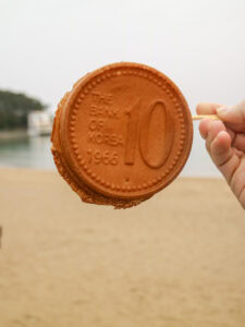Hand holding a cookie shaped like a 10 South Korean won coin.