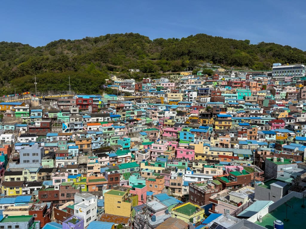 Colorful hillside houses in Busan with a green mountain backdrop.