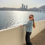 Woman enjoying Busan waterfront view with city skyline in background.