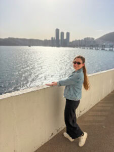 Woman enjoying Busan waterfront view with city skyline in background.