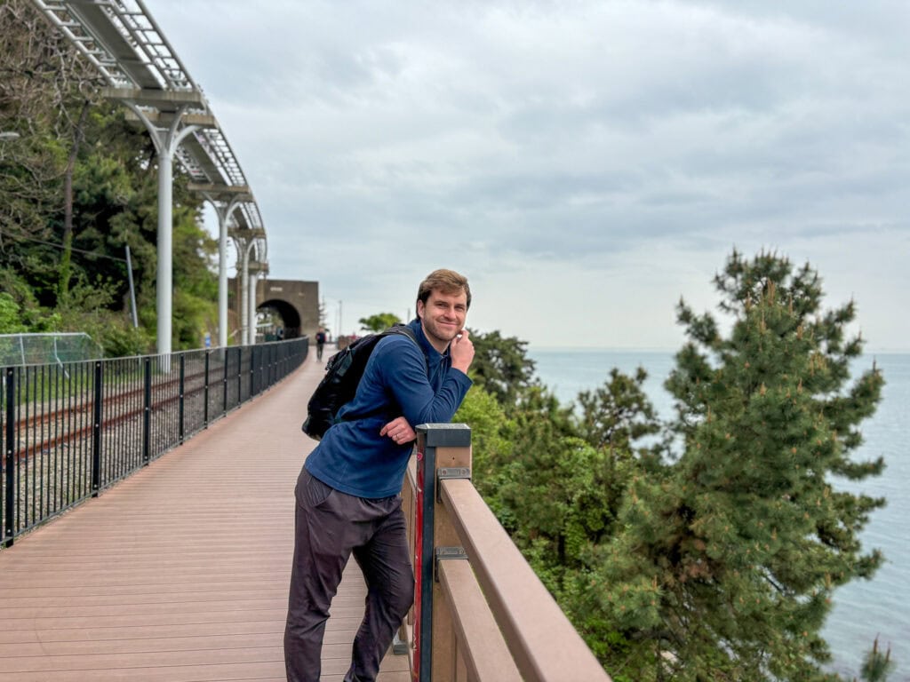 Traveler enjoying scenic coastal view from a walkway in Busan, South Korea.
