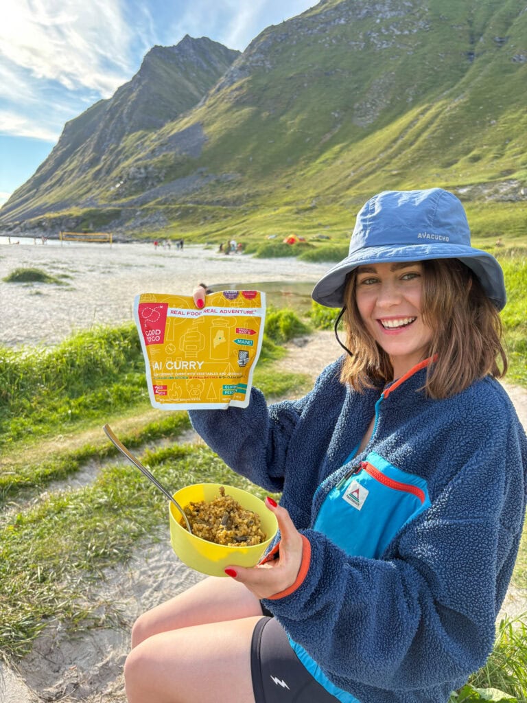 Woman enjoying gluten-free curry outdoors in Lofoten mountains.
