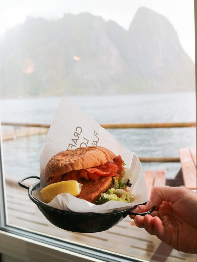 Fresh fish sandwich with lemon on a boat deck with mountain view.