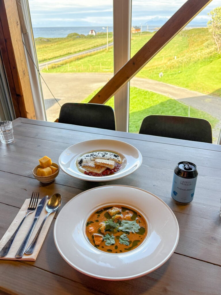 Scenic view of Lofoten islands with a table of gluten-free meal inside a cozy cabin.
