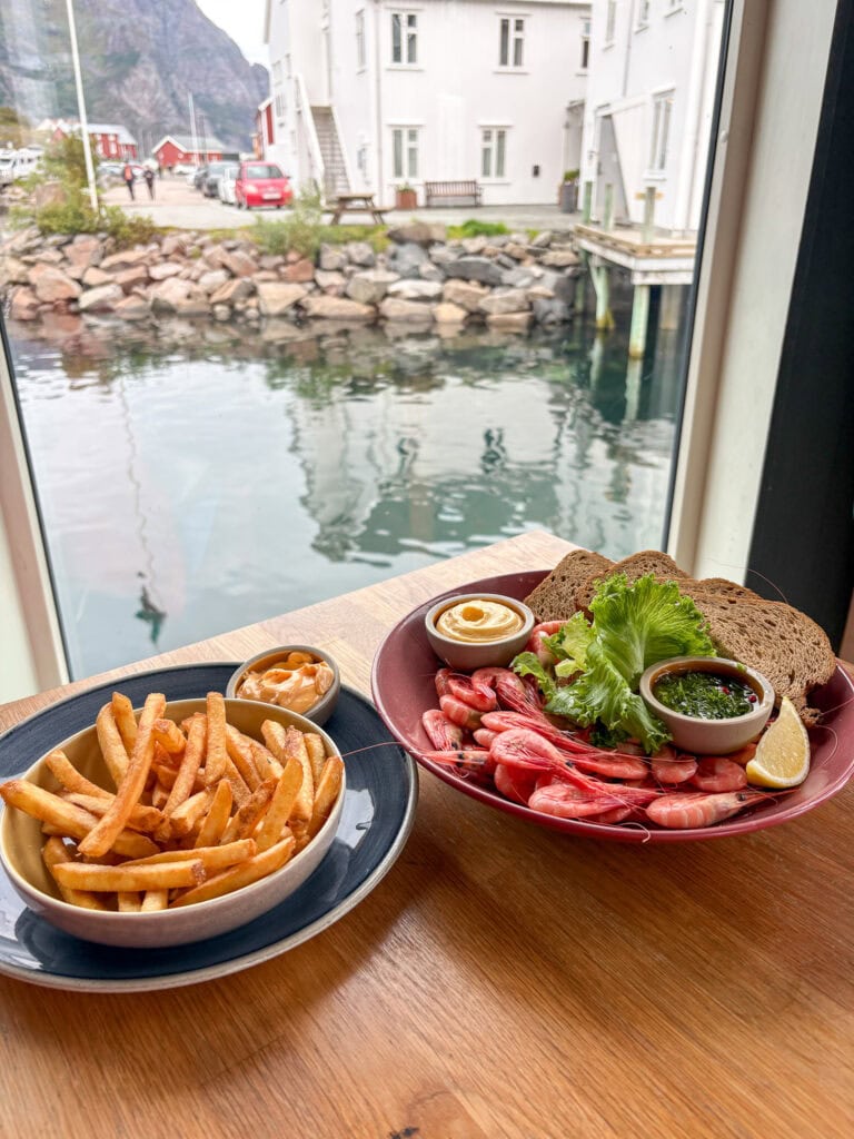 Seafood platter with fries and dipping sauces near a window with harbor view.