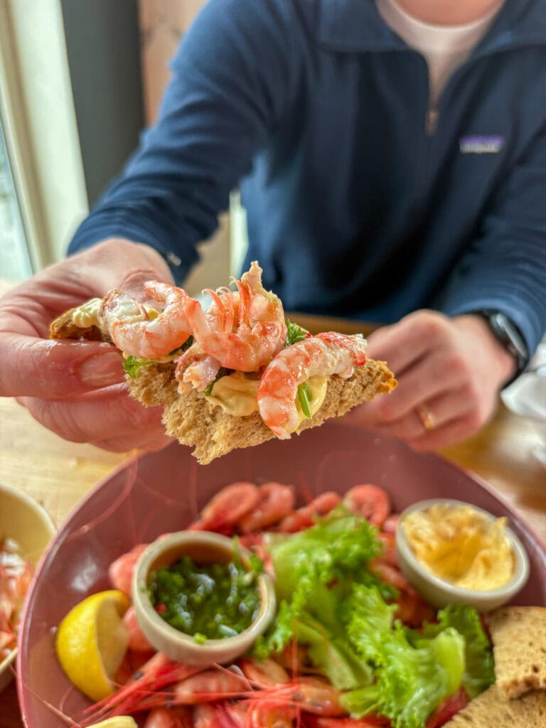 Close-up of a shrimp canapé with a seafood platter in the background.