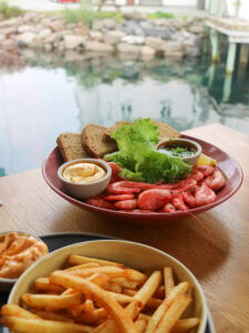 Seafood platter with shrimp, bread, and dipping sauces near a waterfront.