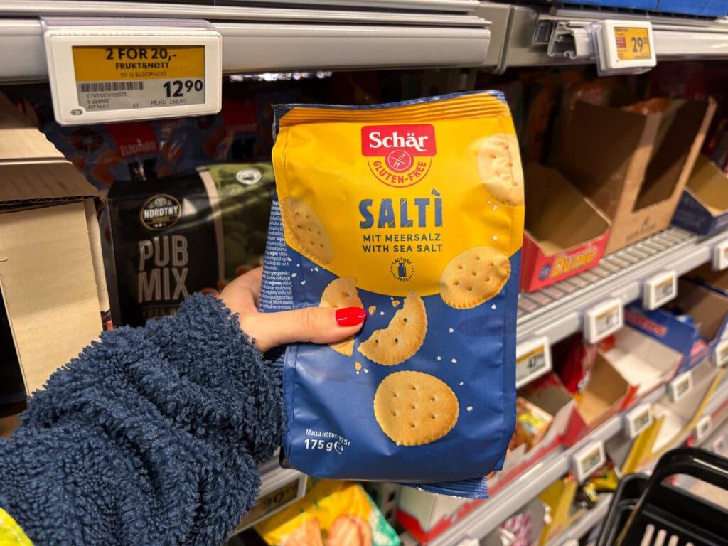 Person holding a bag of sea salt crackers in a grocery store aisle.