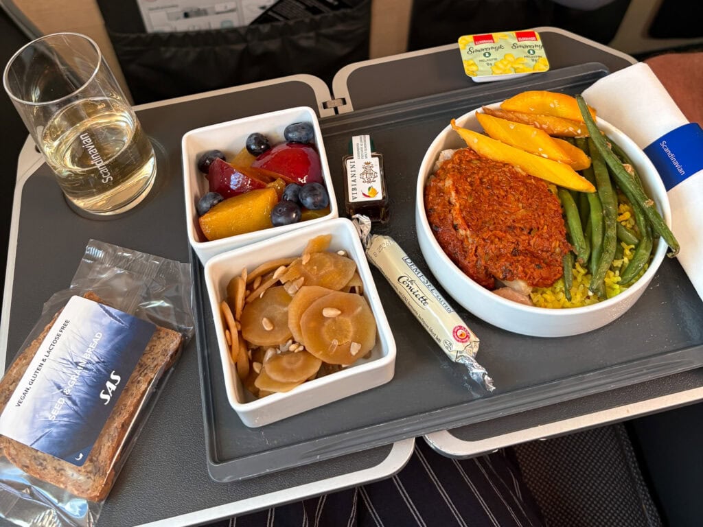 Gluten-free meal with fruit, vegetables, and dessert on an airplane tray.
